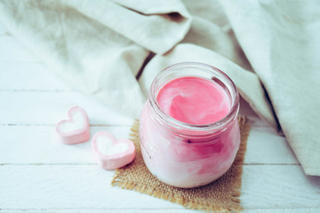 Fototapeta na wymiar Pink milkshake with heart shape marshmallows on wood background