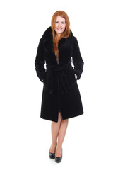 Redhead young woman in black fur coat isolated on white