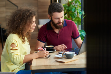 Young students working using laptop, working in restaurant.