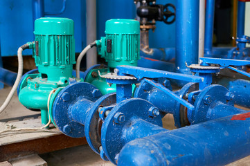 Fototapeta na wymiar Two green electric pump on a water pipeline painted in blue. Industrial background.