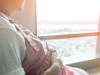 pregnant woman sitting near window waiting for her baby