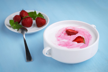 Homemade yogurt with fresh strawberries on a blue wooden background