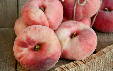 Saturn peach or Dough nut peaches on wooden background and sack cloth.