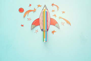 Back to school concept. rocket, space elements shapes cut from paper and painted over wooden blue background.