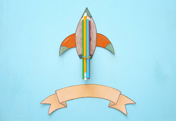 Back to school concept. rocket, space elements shapes cut from paper and painted over wooden blue background.