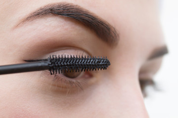 a woman paints her eyes with mascara. The concept of beauty, make-up, make-up