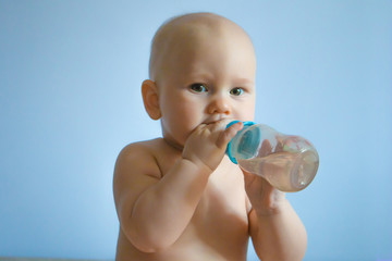 portrait of carefree happy baby holding a pacifier with milk in his hands