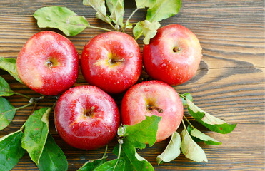 Red apples or Gala apples with fresh leaf , water drop and space on wooden background.