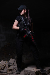 Naklejka premium Girl with rifle on dark background in ruins