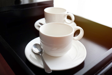 White coffee mug with spoon on black tray