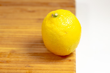 One lemon on a cutting board on a kitchen table waiting to be sliced