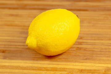 One lemon on a cutting board on a kitchen table waiting to be sliced
