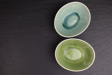two glazed ceramic bowls on black slate plate