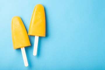 Orange popsicles with juice on a blue bacground. Ice pops, flat lay, top view with copy space - obrazy, fototapety, plakaty