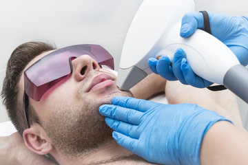 A young man on a procedure of laser hair removal in the salon of aesthetic beauty.