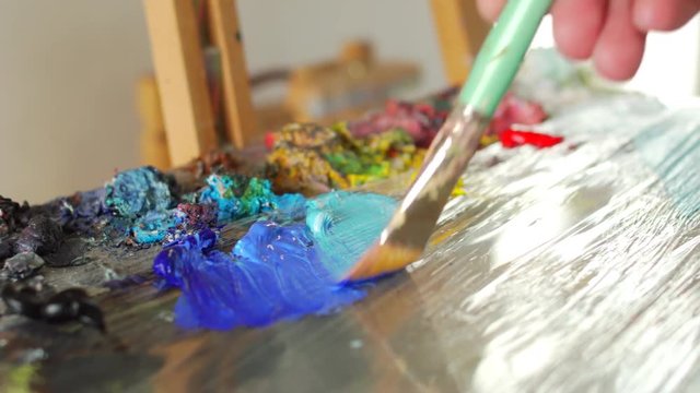 artist stirs paint brush before drawing painting
