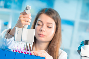 student woman with multi pipette and other PCR items in microbiological / genetic laboratory
