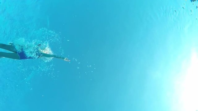 Underwater View Of A Little Girl Swimming In Pool, View From Below