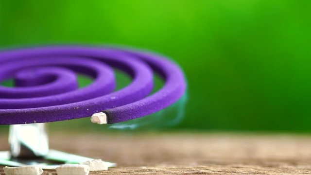 Slow Motion : Violet mosquito repellent and white smoke on wooden table with green blur light space background