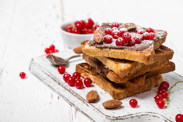 stack of fried toast with chocolate cream, red currant and almon