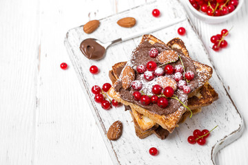 stack of fried toast with chocolate cream, red currant and almonds