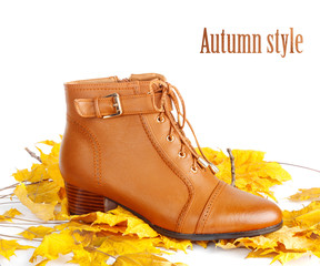 Fototapeta na wymiar Pair of brown female boots with autumn leaves on white background