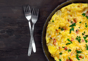 Traditional rustic omelette with bacon, pasta and greens