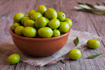 Fresh green olives ina a bowl on wooden table