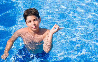 Young child on holidays at the swimming pool by the beach very happy pointing with hand and finger...