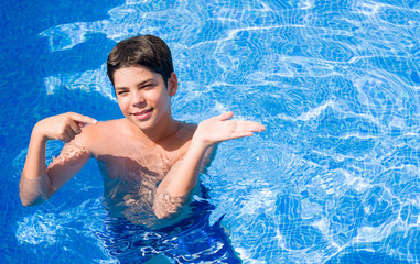 Young child on holidays at the swimming pool by the beach very happy pointing with hand and finger
