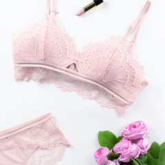 Woman elegant pink lace bra and panties, flowers, jewelry. Stylish lingerie flat lay. Underwear fashion concept