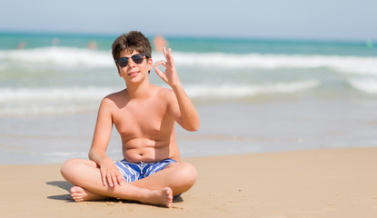 Young child on holidays at the beach doing ok sign with fingers, excellent symbol