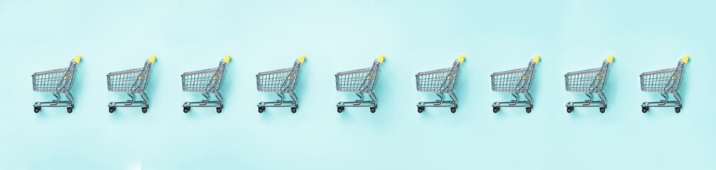 Shopping cart on blue background. Minimalism style. Creative design. Top view with copy space. Shop trolley at supermarket. Sale, discount, shopaholism concept. Consumer society trend