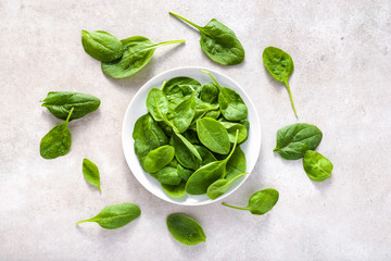 Fresh spinach. Green vegetable leaves on plate, healthy food, vegetarian diet concept.
