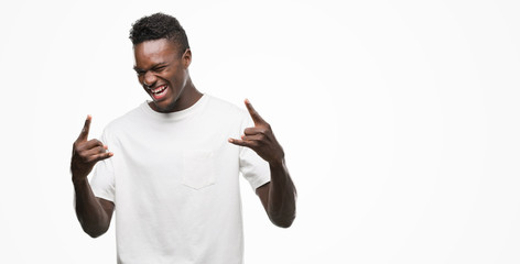 Young african american man wearing white t-shirt shouting with crazy expression doing rock symbol...