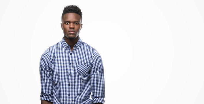 Young African American Man Wearing Blue Shirt With Serious Expression On Face. Simple And Natural Looking At The Camera.