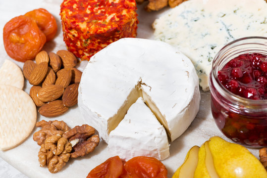 assortment of delicacy cheeses and snacks on board, top view closeup