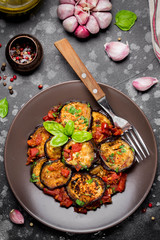 Fried eggplant slices with tomatoes, herbs and garlic, tasty vegetarian summer lunch. Grilled aubergine