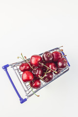 Ripe cherries in a shopping cart isolated