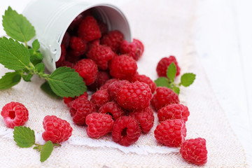 Ripe raspberries in small bucket, wooden background