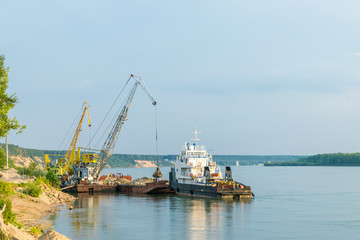 The crane unloads sand from the barge