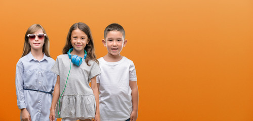 Group of boy and girls kids over orange background with a happy face standing and smiling with a confident smile showing teeth