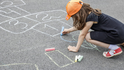child paints chalk classics on the asphalt