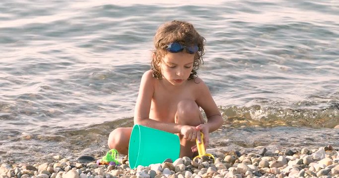 Cute curly-haired Boy Playing On The Sea Beach.