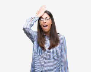 Young beautiful hispanic business woman surprised with hand on head for mistake, remember error....