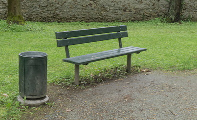 empty bench near a trash can in a park