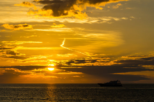 USA, Florida, Painted orange burning sunset sky landscape with yacht on water at key west