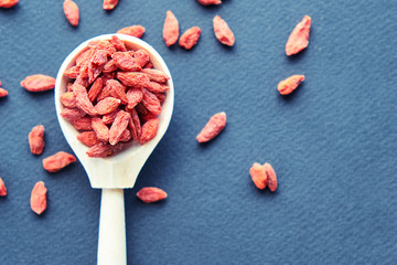 Goji in bowl on wood table. Top view of fresh goji in scoop and bowl. Goji in heart shape on table