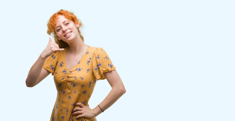 Young redhead woman smiling doing phone gesture with hand and fingers like talking on the telephone. Communicating concepts.