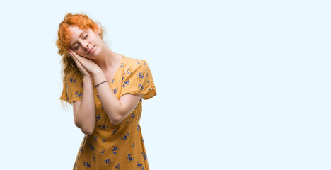 Young redhead woman sleeping tired dreaming and posing with hands together while smiling with closed eyes.
